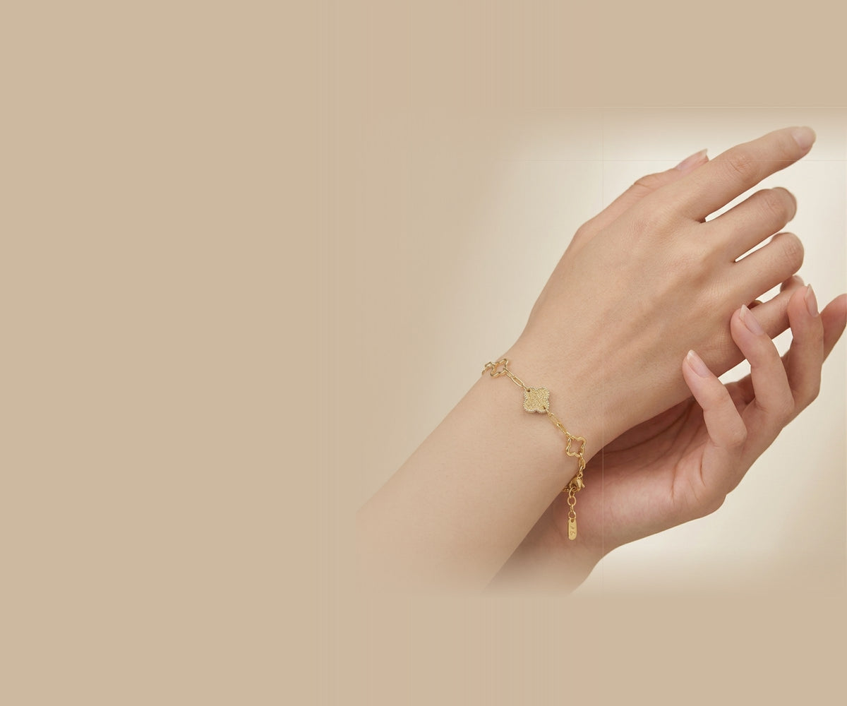Goldfarbenes Gliederarmband mit Kleeblatt-Anhängern am Handgelenk